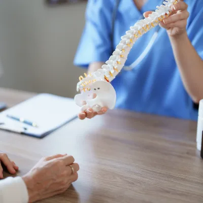 Doctor explaining spinal fusion with a spine model